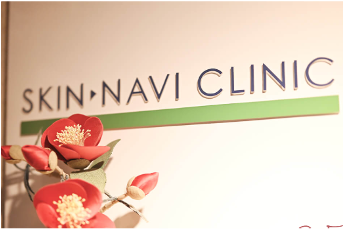 壁面のロゴ「SKIN・NAVI CLINIC」と、椿のフェイクフラワー